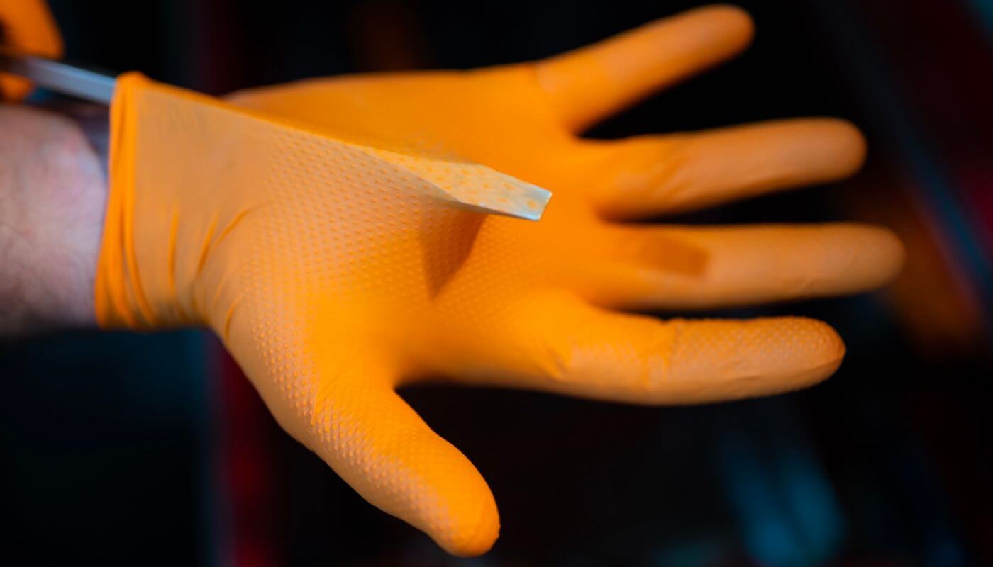 industrial-grade orange nitrile gloves resisting tear from flathead screwdriver